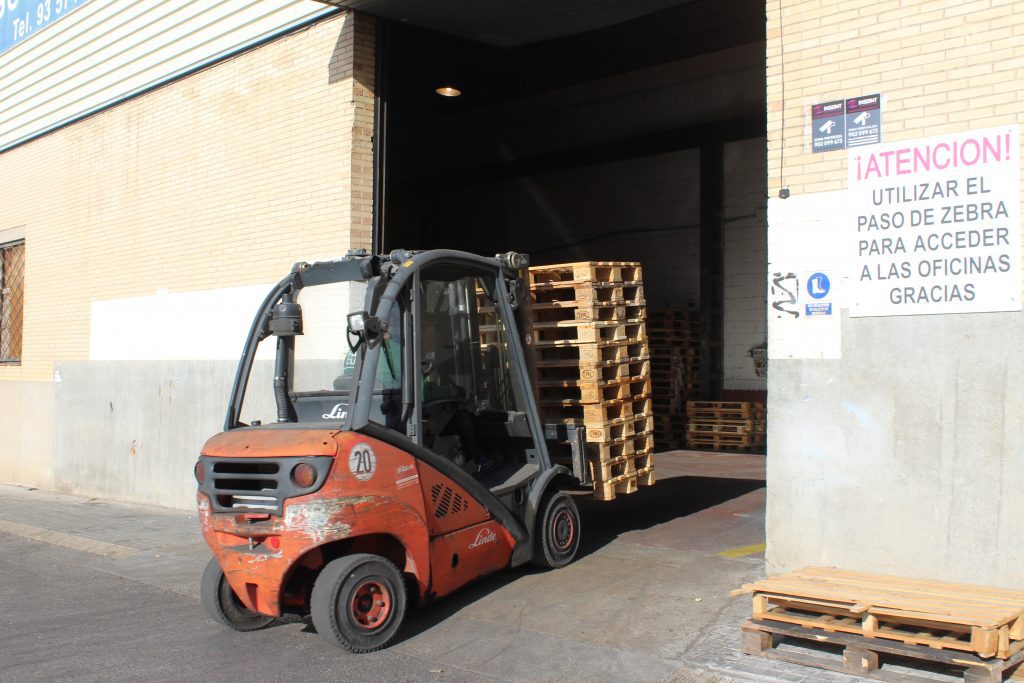 Trabajador transportando palets en una carretilla elevadora para ser almacenados en el almacén